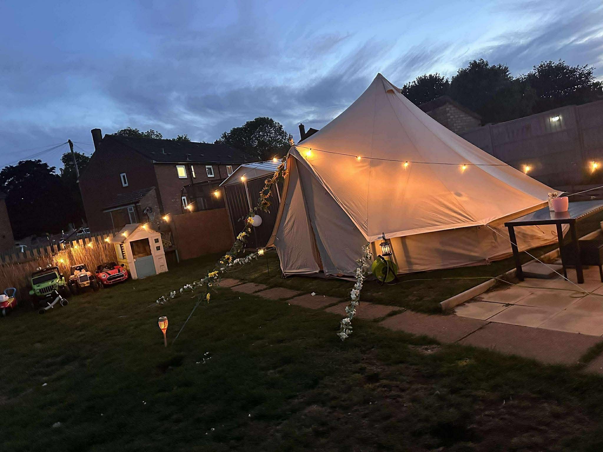 Bell tent lit up with fairy lights at dusk