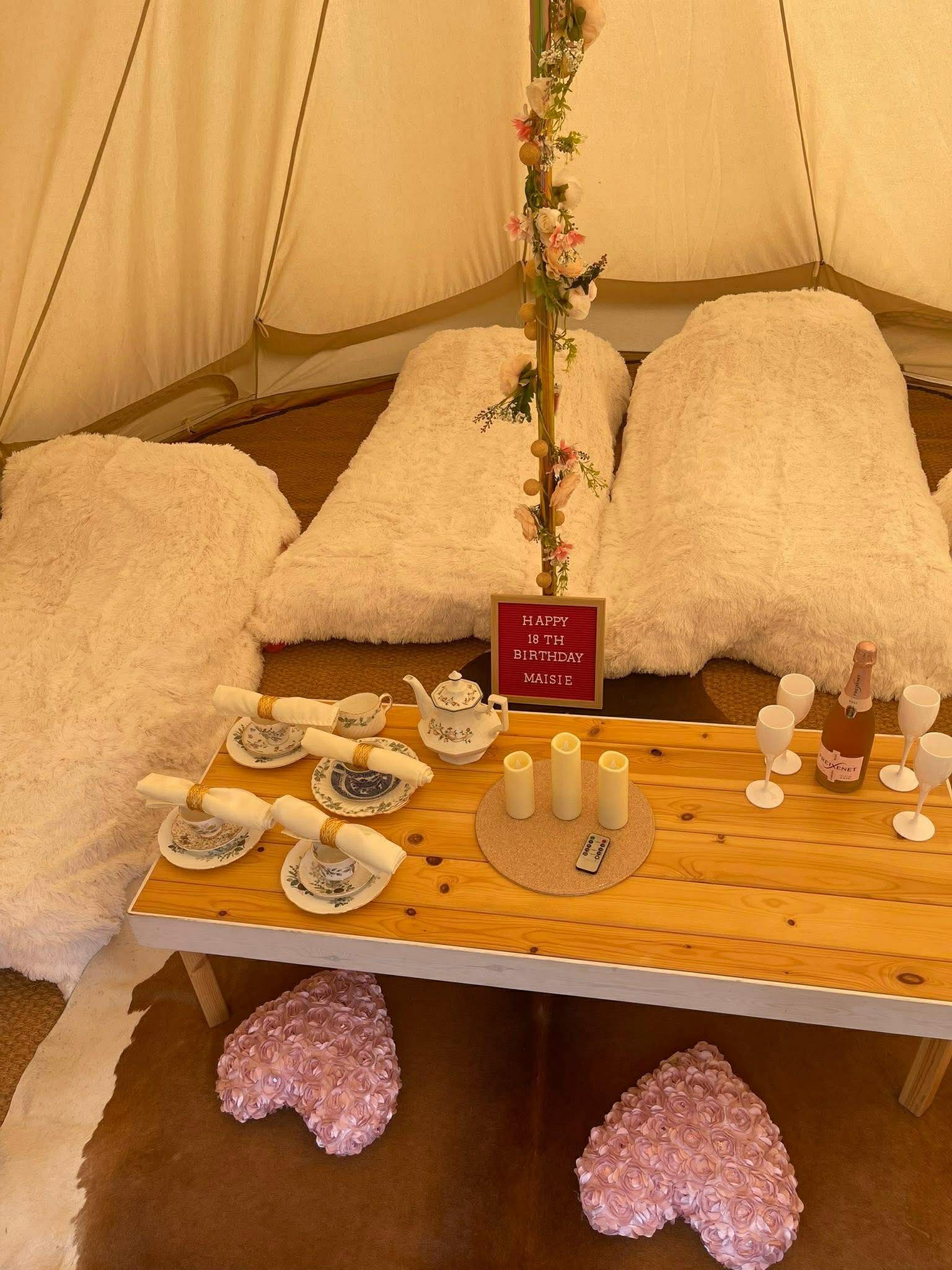 Luxe birthday setup inside bell tent with tea service and prosecco