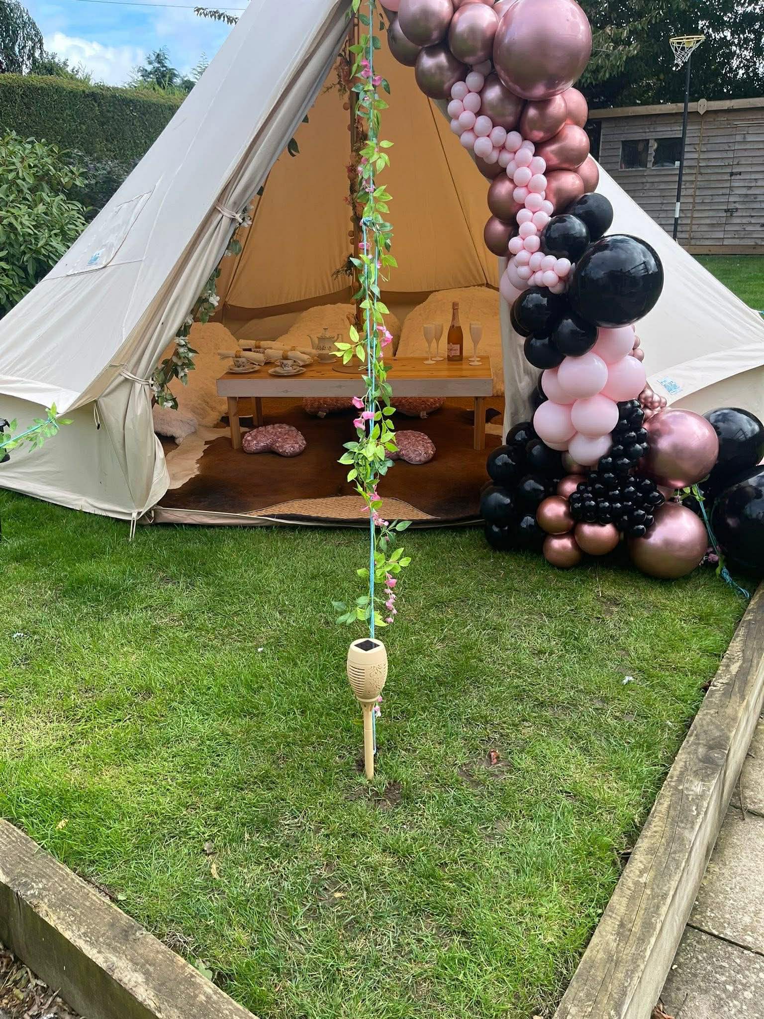 Bell tent set up in garden with pink and black balloon arch