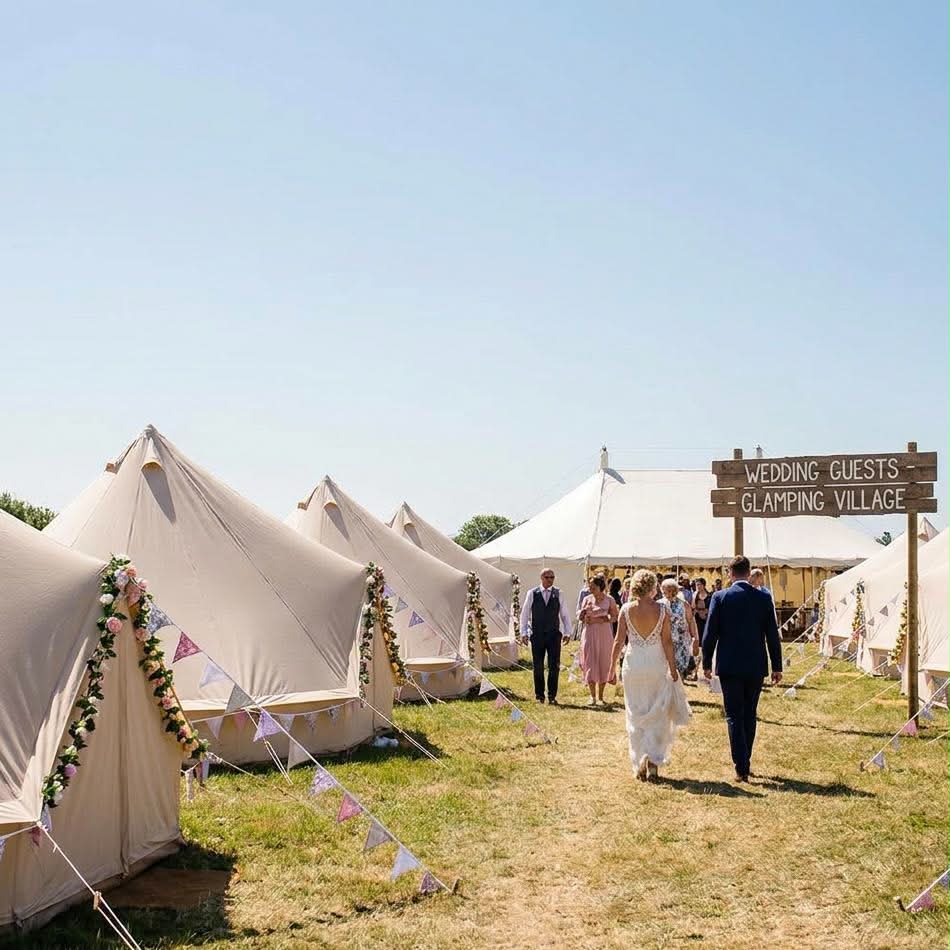 Wedding guests glamping village with bell tents and sign